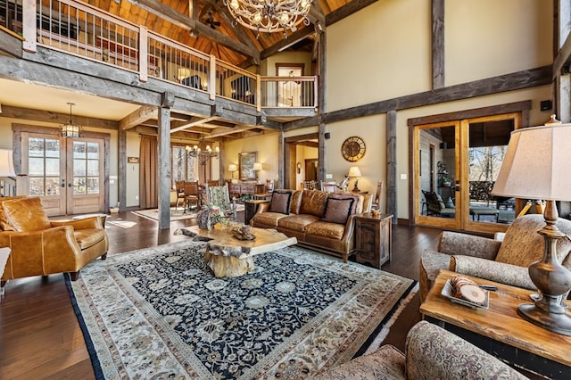 living room with baseboards, a chandelier, dark wood finished floors, french doors, and high vaulted ceiling