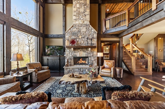 living room featuring a fireplace, stairs, a towering ceiling, and wood finished floors