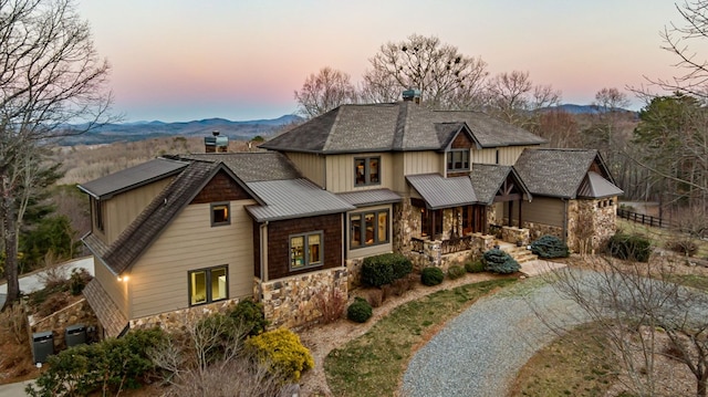 craftsman house with a mountain view, stone siding, and a chimney