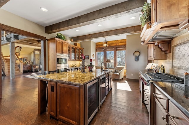 kitchen featuring tasteful backsplash, beverage cooler, a center island with sink, brown cabinetry, and stainless steel appliances