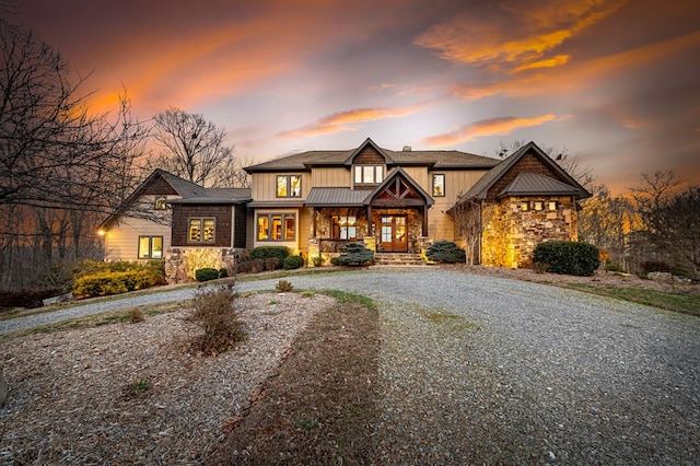 view of front of house featuring stone siding, curved driveway, and board and batten siding