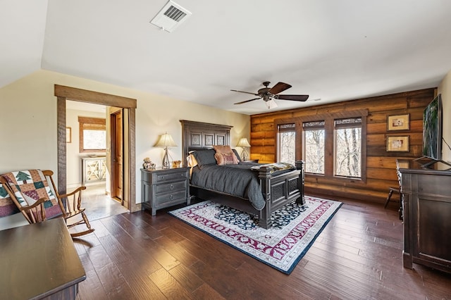 bedroom featuring dark wood finished floors, visible vents, and rustic walls