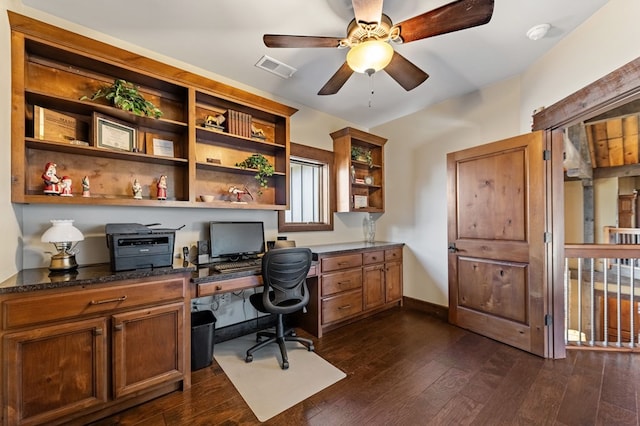 office featuring a ceiling fan, baseboards, visible vents, dark wood-type flooring, and built in desk