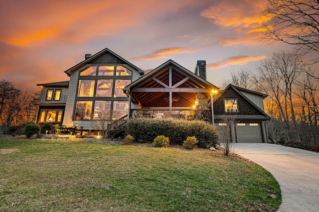 view of front of property with an attached garage, a lawn, a chimney, and driveway