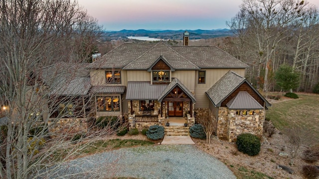 view of front facade featuring a mountain view, french doors, stone siding, and a chimney