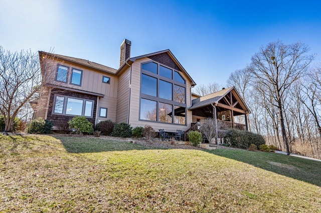 rear view of property featuring a lawn, covered porch, and a chimney