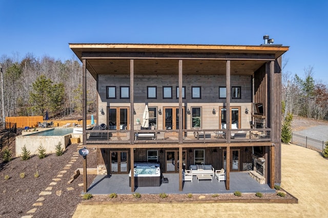 back of property with outdoor lounge area, fence, french doors, an outdoor hot tub, and a patio area