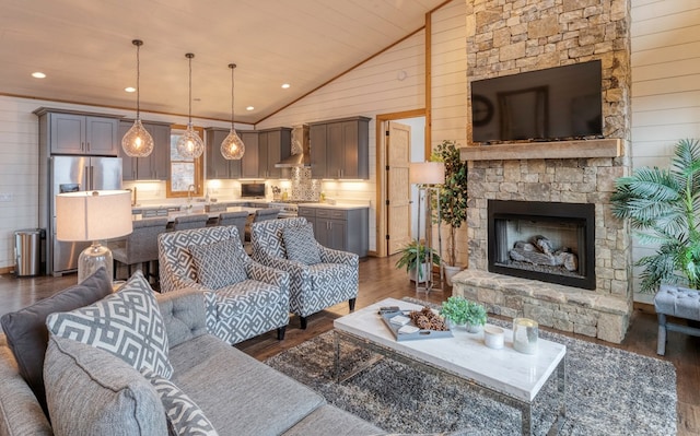 living area with wood walls, dark wood finished floors, high vaulted ceiling, and a fireplace