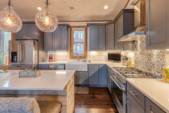 kitchen featuring high end appliances, wall chimney range hood, dark wood-type flooring, recessed lighting, and a sink