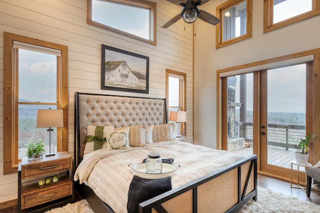 bedroom featuring multiple windows, wood walls, wood finished floors, and access to exterior