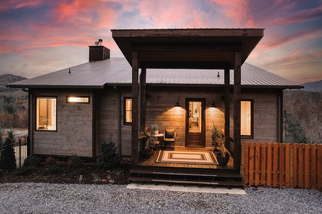 exterior space featuring fence, a chimney, and metal roof