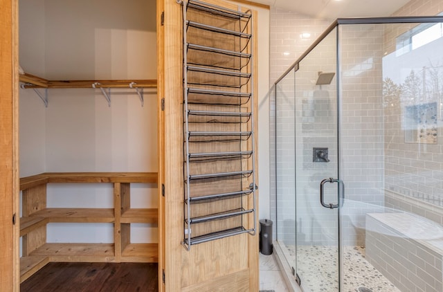 full bathroom with a stall shower, wood finished floors, and a spacious closet