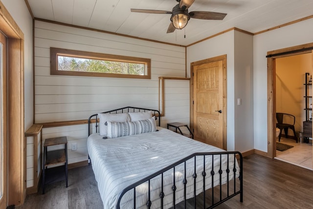 bedroom with crown molding, wood walls, wood finished floors, and a barn door