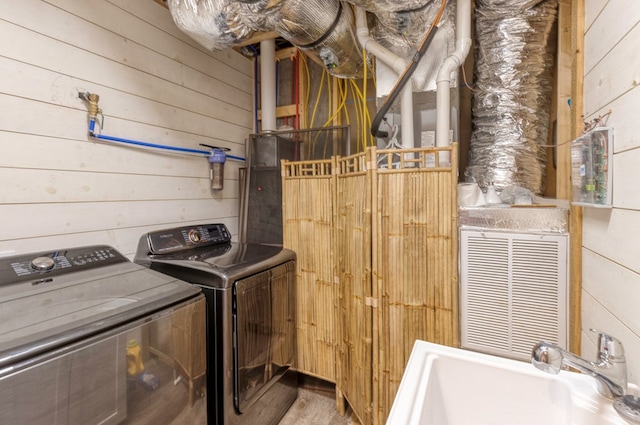 washroom with separate washer and dryer, a sink, and wooden walls