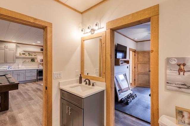 full bath featuring crown molding, beverage cooler, wood finished floors, and vanity