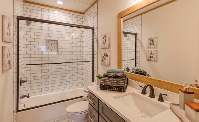 full bath featuring vanity, bath / shower combo with glass door, and toilet