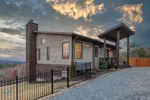 view of front of house featuring fence private yard, a chimney, and a porch
