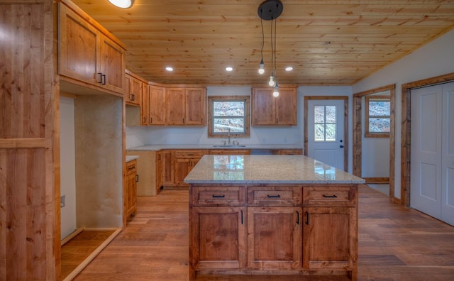 kitchen with light wood-type flooring, a center island, sink, and hanging light fixtures