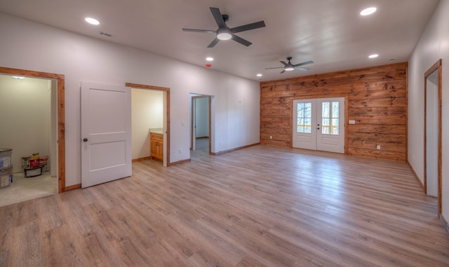 interior space with french doors, light hardwood / wood-style flooring, wood walls, and ceiling fan