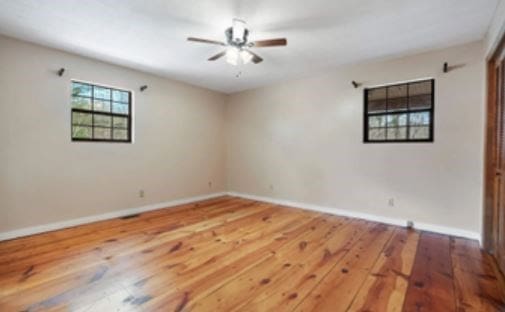 unfurnished room with a ceiling fan, baseboards, and hardwood / wood-style floors