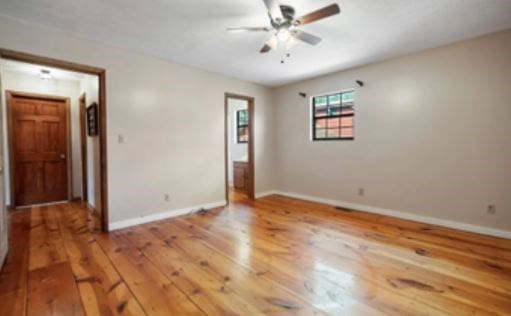 spare room with a ceiling fan, baseboards, and hardwood / wood-style floors