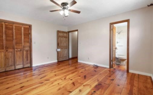 unfurnished bedroom with connected bathroom, baseboards, and hardwood / wood-style flooring