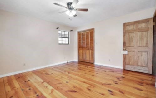 unfurnished room featuring wood finished floors, a ceiling fan, and baseboards