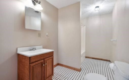 bathroom with vanity, walk in shower, toilet, and baseboards