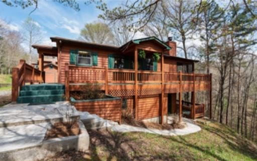 rear view of house with a deck, driveway, and a chimney