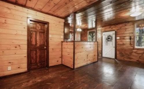 empty room with wooden ceiling, wood finished floors, and wooden walls