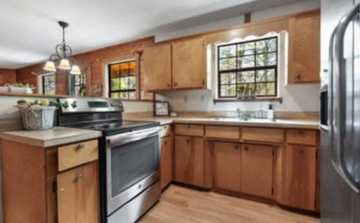 kitchen with a peninsula, appliances with stainless steel finishes, light countertops, and light wood-style flooring