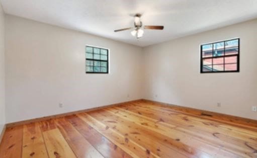 empty room with a ceiling fan, a wealth of natural light, baseboards, and light wood finished floors