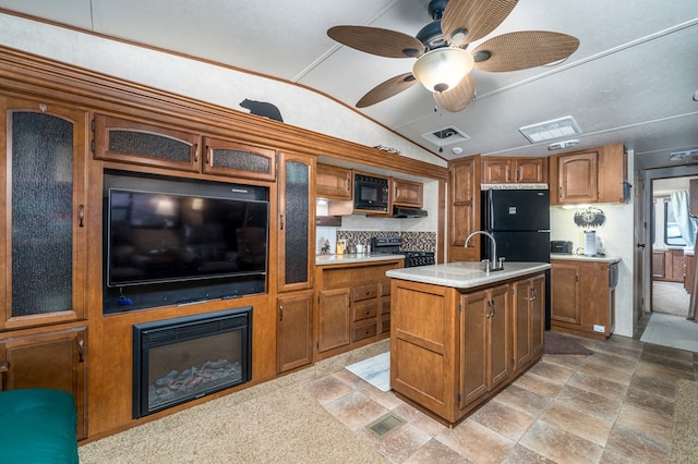 kitchen with ceiling fan, sink, lofted ceiling, a kitchen island with sink, and black appliances