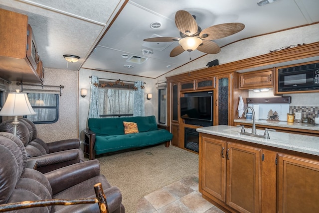 kitchen with ceiling fan, light colored carpet, black microwave, and vaulted ceiling