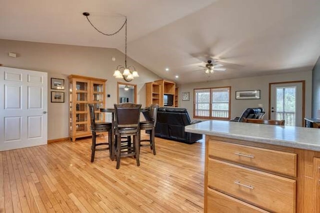 dining space with lofted ceiling, light wood-style flooring, and ceiling fan with notable chandelier