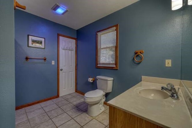 bathroom with toilet, tile patterned flooring, baseboards, and vanity