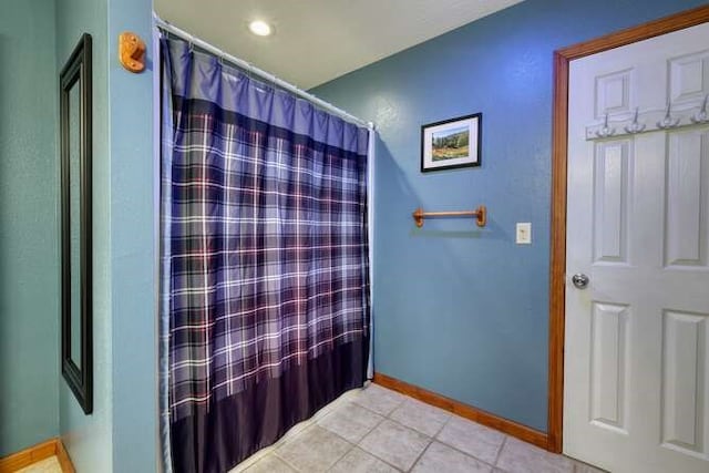 full bathroom featuring tile patterned flooring, curtained shower, and baseboards