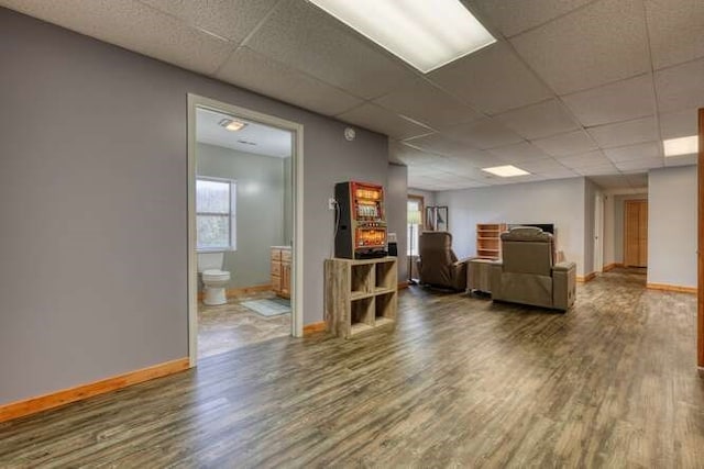 living room with a drop ceiling, wood finished floors, and baseboards