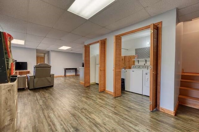 finished basement featuring a paneled ceiling, stairs, washer and dryer, and wood finished floors