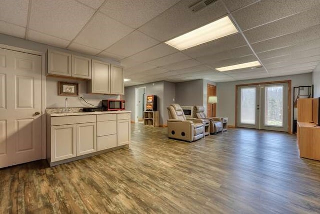 kitchen featuring visible vents, open floor plan, a sink, wood finished floors, and a drop ceiling