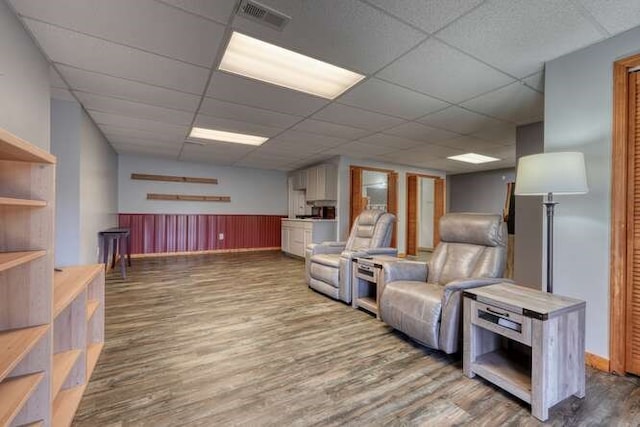 living area featuring a wainscoted wall, a paneled ceiling, wood finished floors, and visible vents