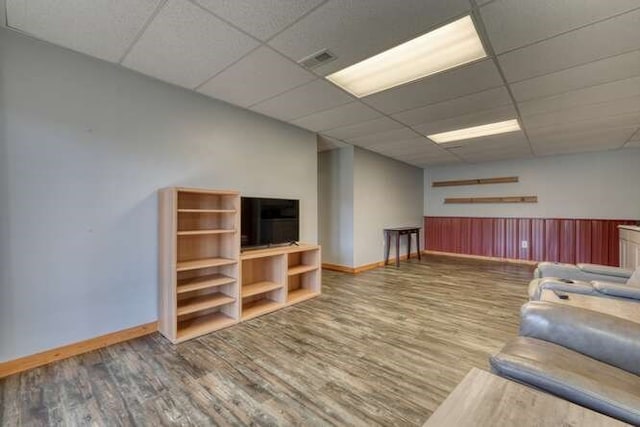 unfurnished living room featuring a paneled ceiling, a wainscoted wall, visible vents, and wood finished floors