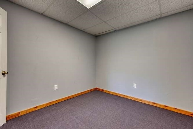 carpeted spare room with baseboards and a drop ceiling