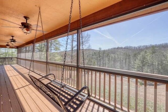 wooden deck featuring ceiling fan and a wooded view