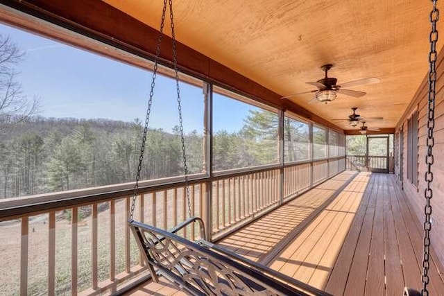 unfurnished sunroom featuring a ceiling fan and a view of trees