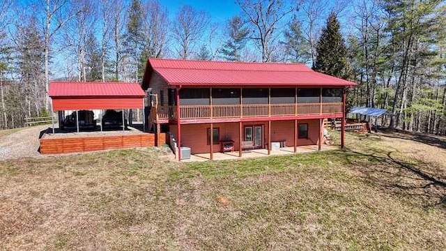 rear view of house with metal roof, a yard, and a patio area