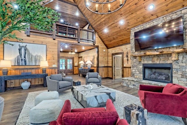 living room with high vaulted ceiling, wooden walls, hardwood / wood-style flooring, and a fireplace