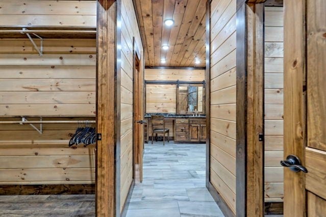 hall featuring wood ceiling and wood walls