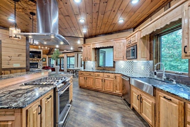 kitchen featuring extractor fan, wood walls, sink, and stainless steel appliances