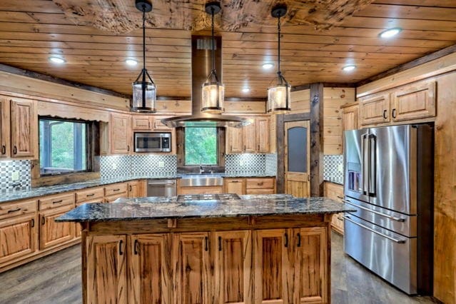 kitchen featuring stainless steel appliances, hanging light fixtures, a center island, and dark stone countertops